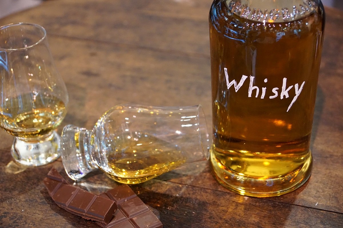 Zwei Whiskygläser und eine Flasche, auf der Whisky steht und die ihn enthält
